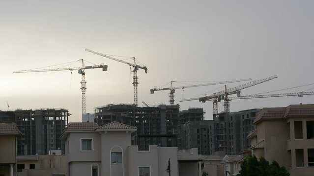 Construction site of new buildings in Egypt, acres of luxurious real estate residential buildings under construction with cranes, selective focus