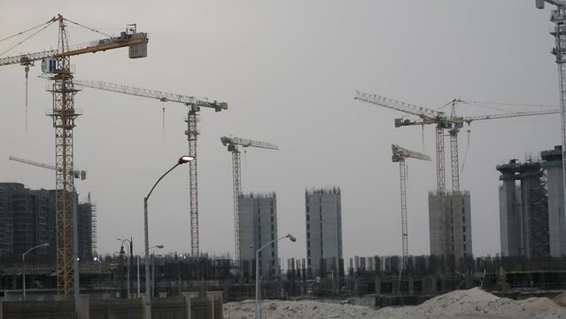 Construction site of new buildings in Egypt, acres of luxurious real estate residential buildings under construction with cranes, selective focus