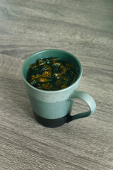 Dandelion flower tea in a cup. Homemade herbal tea as delicious and healthy drink. It has  improves liver health and antioxidant properties. Toned image.