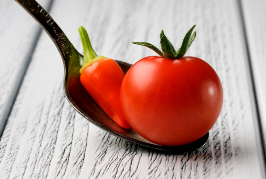 Small red ripe tomato with red hot pepper