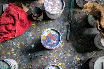 Farbdosen in einem Atelier bei einem Künstler mit vielen bunten Kleksen auf den Dosen und auf dem...