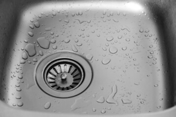 Water drops in a metal sink on stainless steel kitchen sink hole