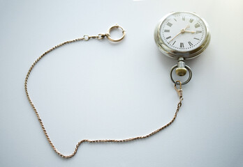 Fototapeta premium Pocket mechanical watch of the last century on a white background.Silver watch with gold chain. Pawnshop. Buying antiques.Search for old things.The passing time.