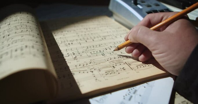 Composer, pencil, and score in inspiring sunlight. Close-up shot, 60fps