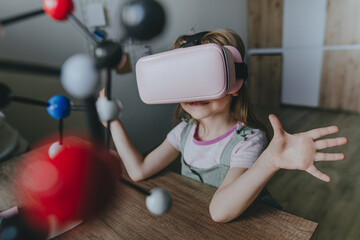 Little girl using VR glasses for learning molecular structure