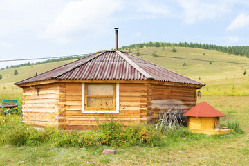 Obraz premium Wooden yurt and a dog house in the form of a yurt in the summer steppe