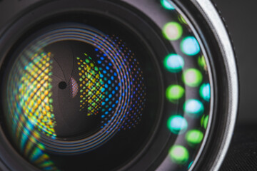 Professional camera photo lens. Details of glass, layer of enlightenment, aperture petals. Light reflections from modern diode lamps. The concept of making visual content. Left side