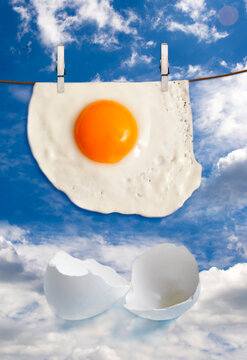 egg omelette hanging on a clothesline and white eggshells over a cloudy sky as a concept of  3D print of food and the future of food production