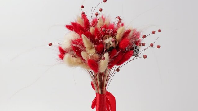 Bouquet of red and yellow laguruses fixed by a red ribbon rotates around its axis