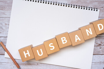 夫のイメージ｜「HUSBAND」と書かれた積み木、ノート、ペン、手