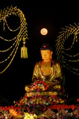 Golden buddha statue in vaisak celebration with full moon background