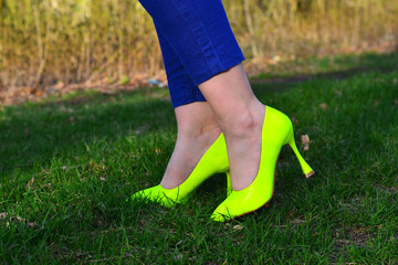 A girl in bright light green shoes, a close-up of her legs. Against the background of bright green grass.
Classic high heel shoes.