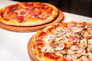 Pizza with salami, bell pepper, tomatoes and cheese, pickles, bacon and sausages on a light background. Close-up, selective focus