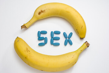 Two yellow bananas surround the blue tablets that make up the inscription sex, like viagra, concept...