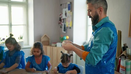 Group of little kids with teacher working with pottery clay during creative art and craft class at school.