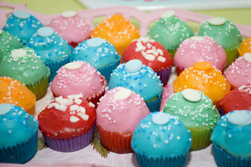 Muffins in various colors with candies on top