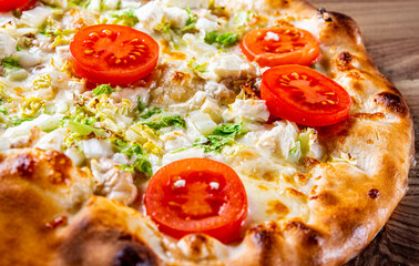 Pizza Caesar with chicken, cheese and tomatoes. Italian pizza on wooden table background