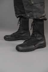 Leather military tactical boots on a Ukrainian soldier on a gray background