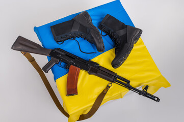 Leather tactical army boots with a Kalashnikov assault rifle lie on the flag of Ukraine