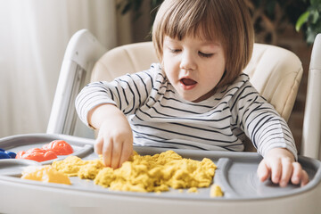 Cute little boy playing with kinetic sand. Development of fine motor skills. Early sensory...