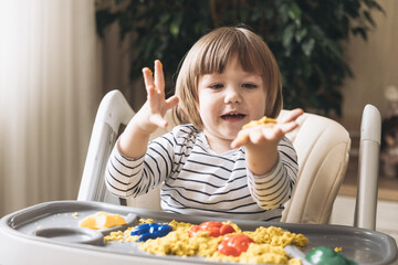 Cute little boy playing with kinetic sand. Development of fine motor skills. Early sensory...