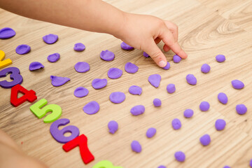 Play-Doh stones and numbers. Counting DIY game. Mathematical task. Play at home. Way of learning. Kid flatten balls when saying a digit.
