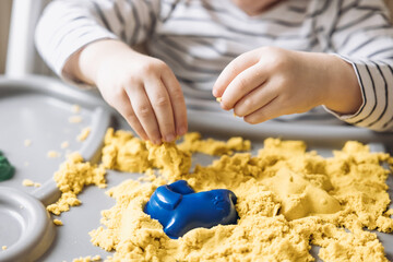 Cute little boy playing with kinetic sand. Development of fine motor skills. Early sensory...