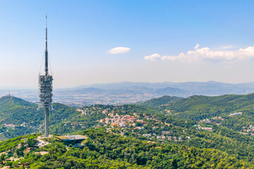 Panorama of Barcelona in summer from Mount Tibidabo under sky with clouds and view of green hills and mountains