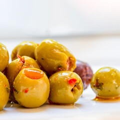 Close up of Pitted Green and black olives with red chilli marinade on a white background
