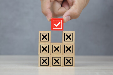 Hand choose wooden block stack with check mark and cross symbol for customer survey service and...