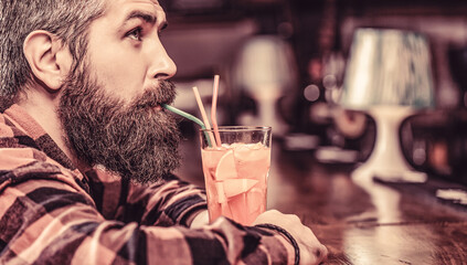 Tropical alcoholic fresh cocktail. Barman in pub or restaurant. Bearded man cocktail. Portrait man, drinking orange juice. Bearded man drink cocktails