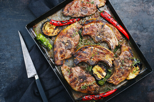 Gegrillte Lammr&uuml;ckensteaks mit Chili und Kr&auml;uter serviert als Draufsicht auf einem rustikalen Metall Tablett