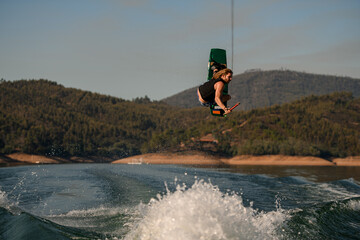 great view of man with wakeboard masterfully jumping high over splashing wave.