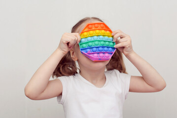 A girl plays with a popular toy multi-colored pop it in the form of an octahedron