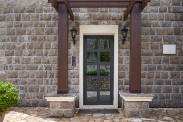 Entrance to the house with glass door and stone finished wall