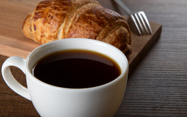 Close-up of croissant with a cup of whole coffee