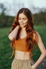Naklejka premium Woman in nature with beautiful long curly hair enjoying the sunset sunshine and smiling while looking at the camera