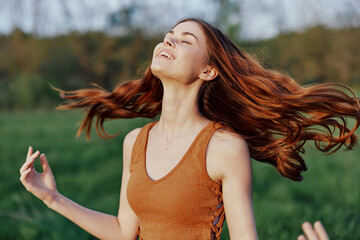 A young woman laughing and smiling merrily in nature in the park with the sunset lighting...