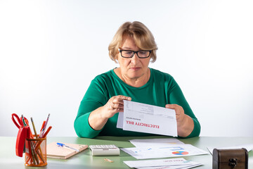 A retired woman examines her electricity bill. The concept of accounting for household expenses,...