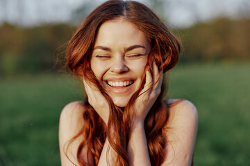 Portrait of a young redheaded woman looking into the camera and smiling, close-up portrait of a laughing woman in the setting sunlight
