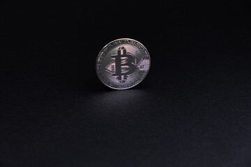 One BitCoin coin close-up with face on silver colour stand bottom centered on back background. Bitcoin BTC Digital crypto currency - Electronic Money. Digital coin international stock exchange.