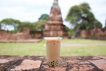 Taiwan ice milk tea with bubble boba, fresh drink and blur old temple in Thailand are background