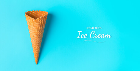An empty waffle cone on a blue background with space to copy. Top view, horizontal.
