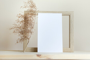 Simple composition with wooden frame and blank white card on yellow background.