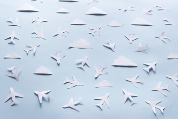 Paper composition with paper planes and white paper clouds on blue background.