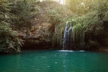 Long exposure waterfall during the day. green forest and rocky mountain. summer time. crystal clear...