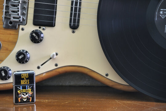 Parte de uma guitarra electrica, isqueiro da banda de rock americana e parte de um &aacute;lbum em vinil tamb&eacute;m da banda famosa, pousados em cima de um suporte de madeira velho