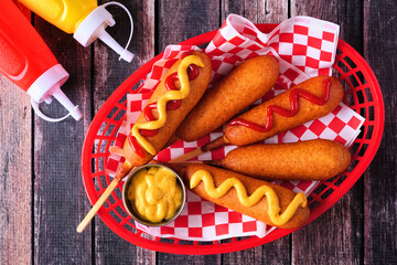 Basket of corn dogs. Top down view over a dark wood background. Summer carnival concept.