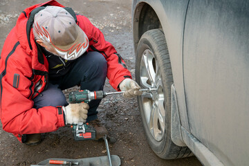 A man is changing the wheels on a car. Safety, car maintenance.