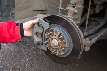 A man replaces the brake pads on a car. Security, service.